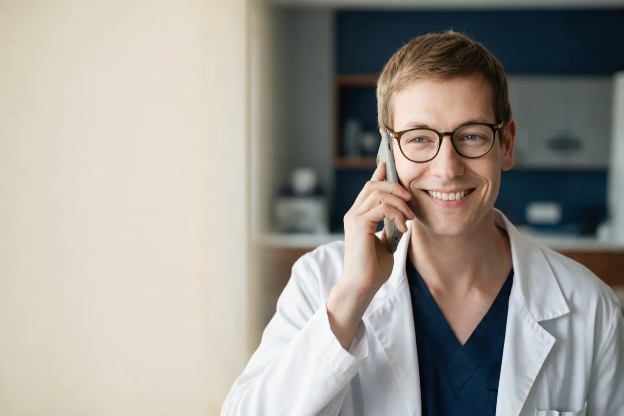 Un médecin souriant répond au téléphone, au cabinet